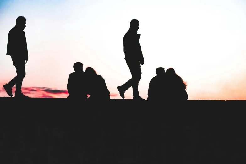 people standing in the sunset on a hill