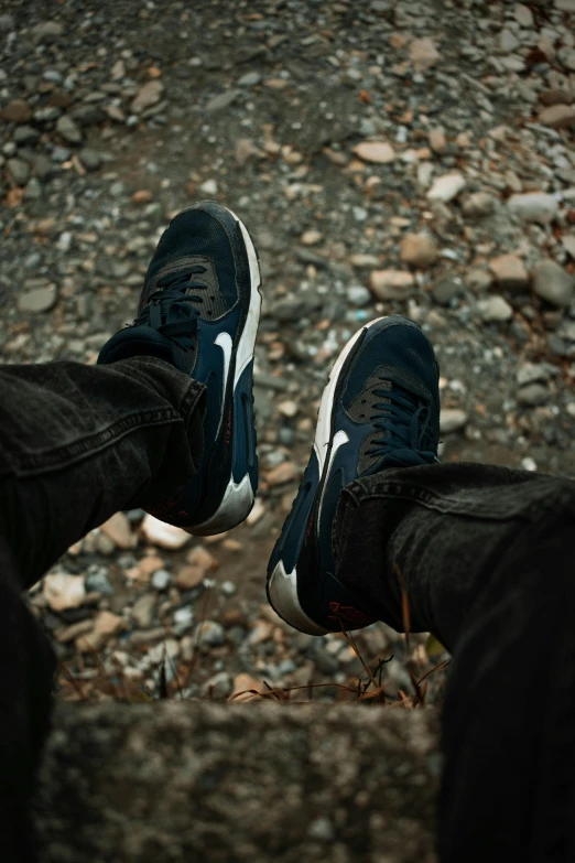 pair of sneakers standing on the ground between legs