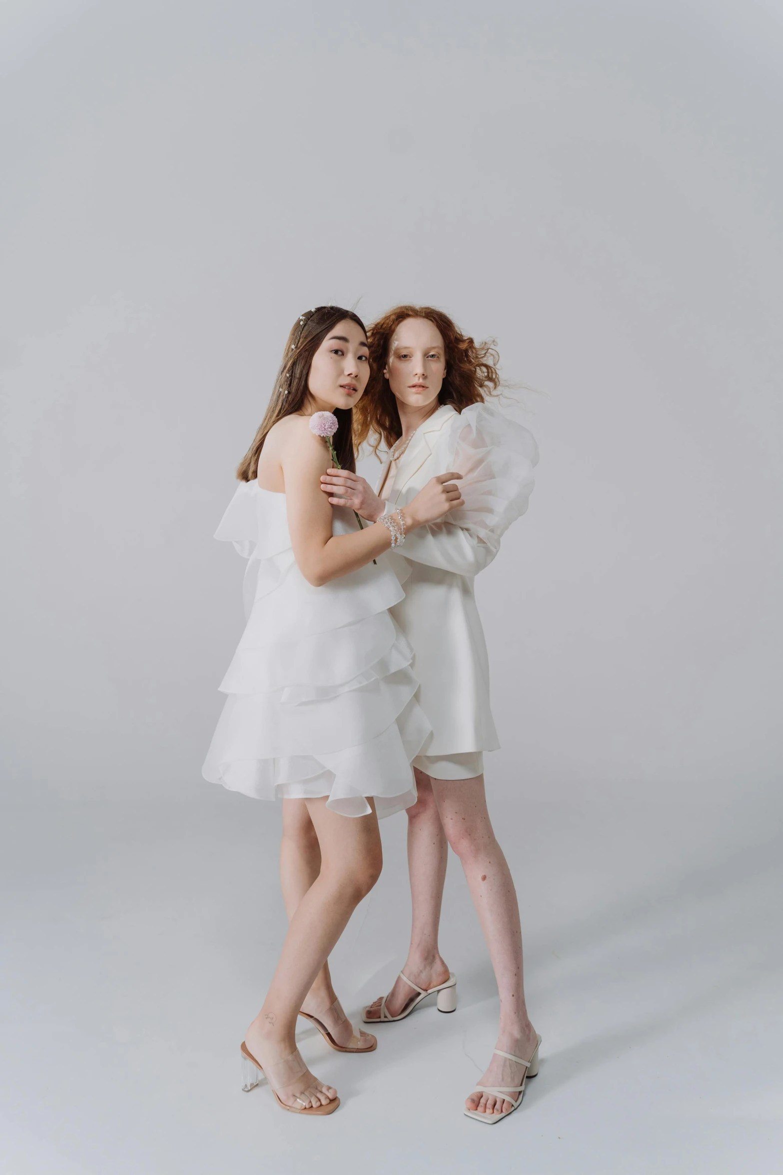 two young women posing for a po in their white dresses