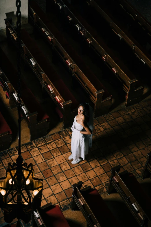 a bride in a white gown stands alone with the sunlight on her face