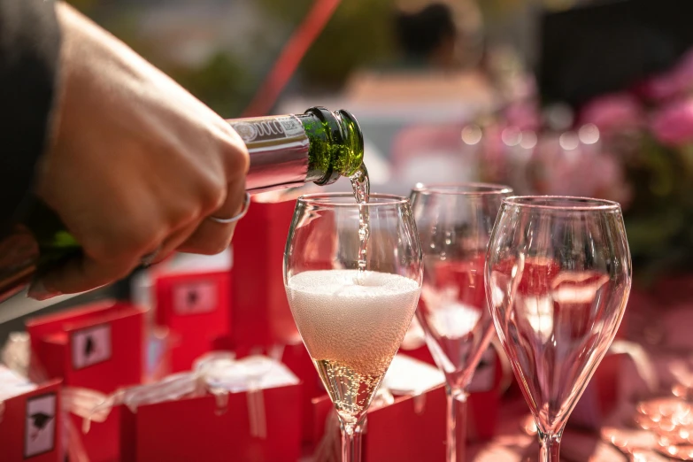 a person pouring champagne into wine glasses for other people