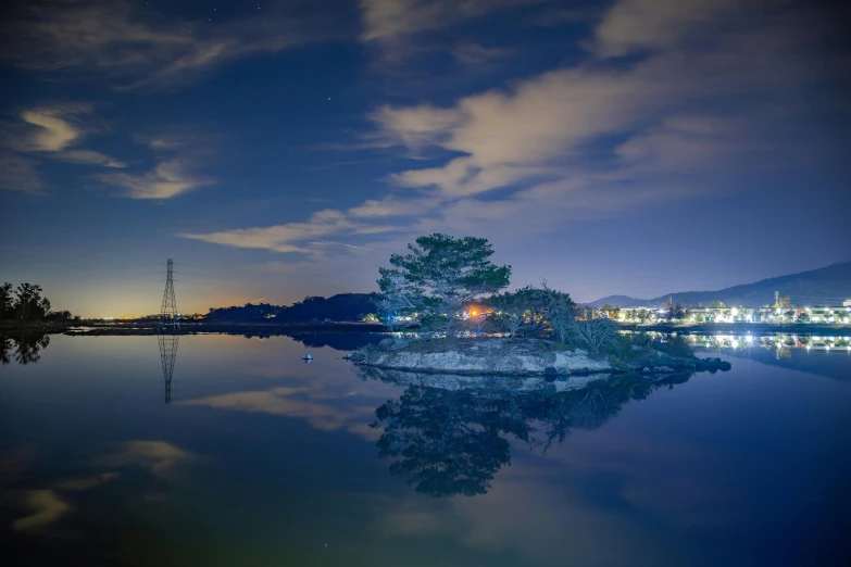a long - exposure picture of an evening scene, with water, city lights and trees