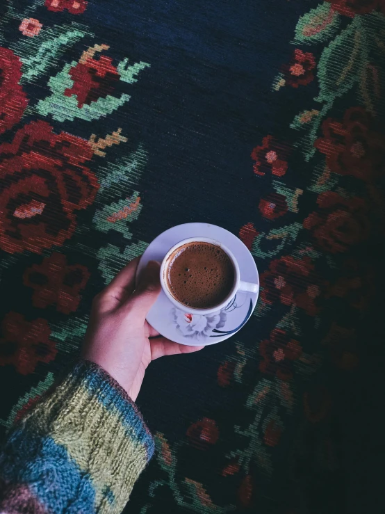 a person holding a cup of coffee on a table