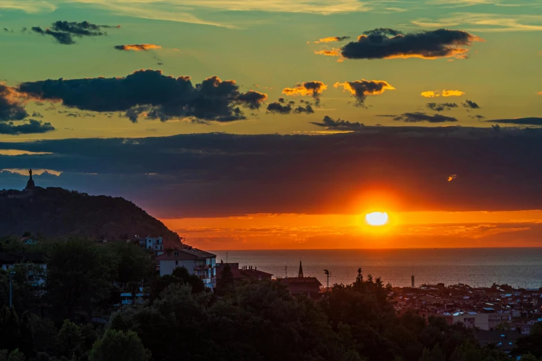 the sun rising over a city next to a body of water