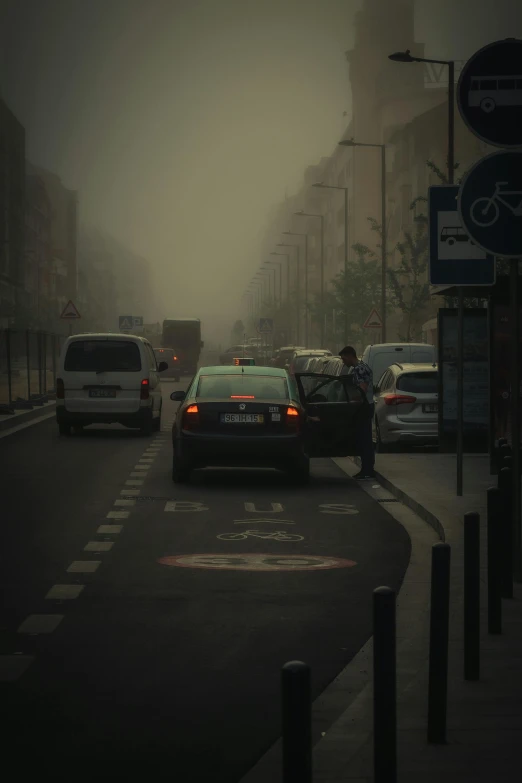 a car is on a city street while the man is out for work