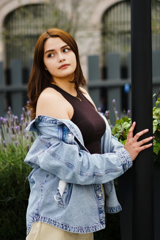 a beautiful young lady with long hair standing next to a pole