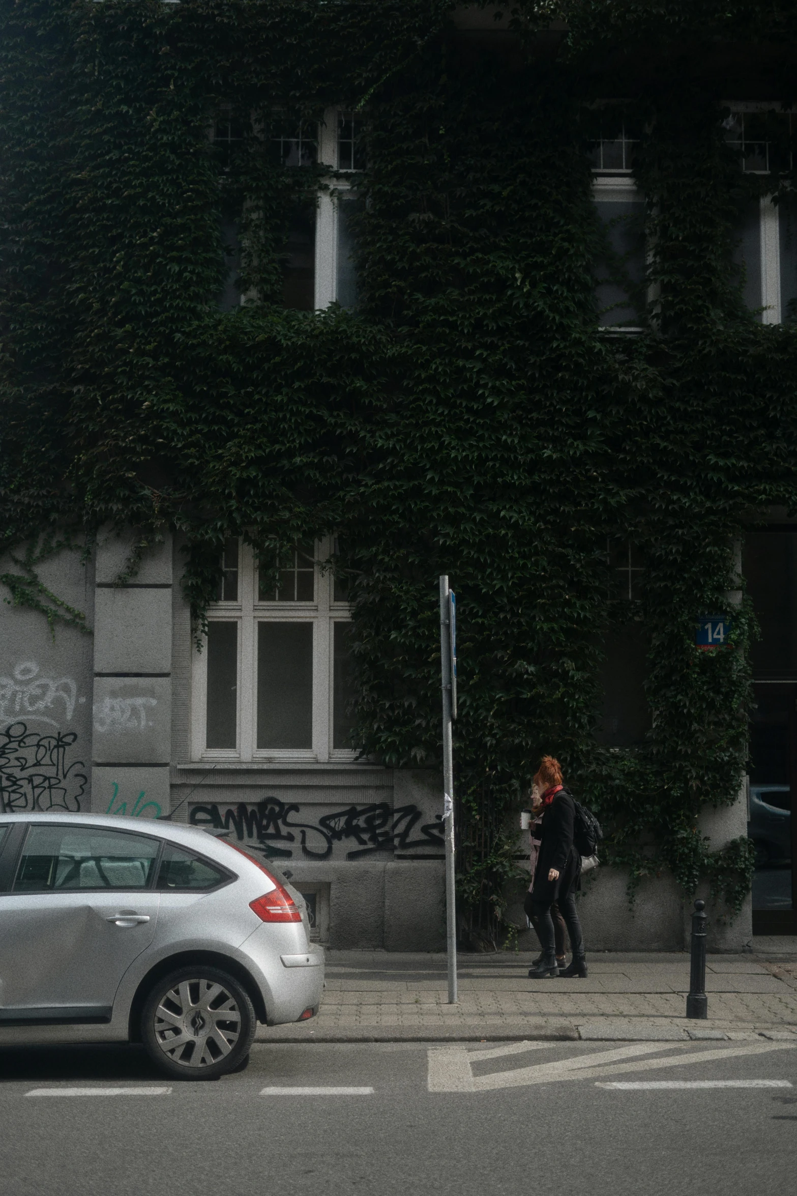 a person walking near a car parked on the side of the road