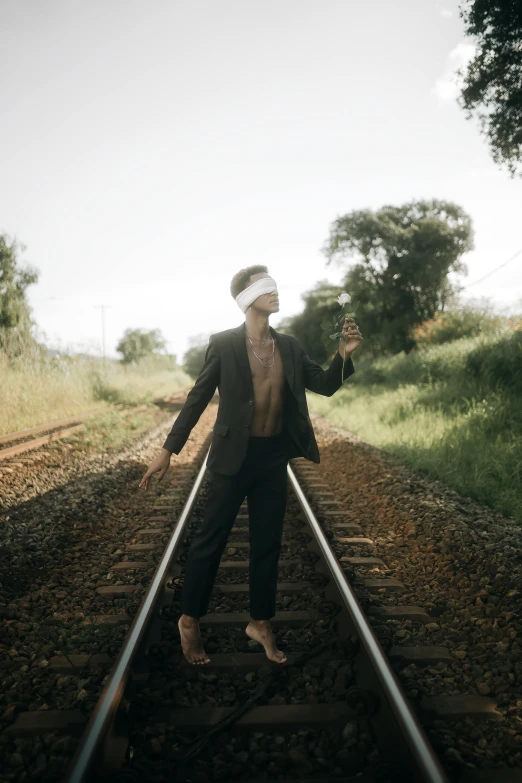 a man standing on train tracks with his arms outstretched