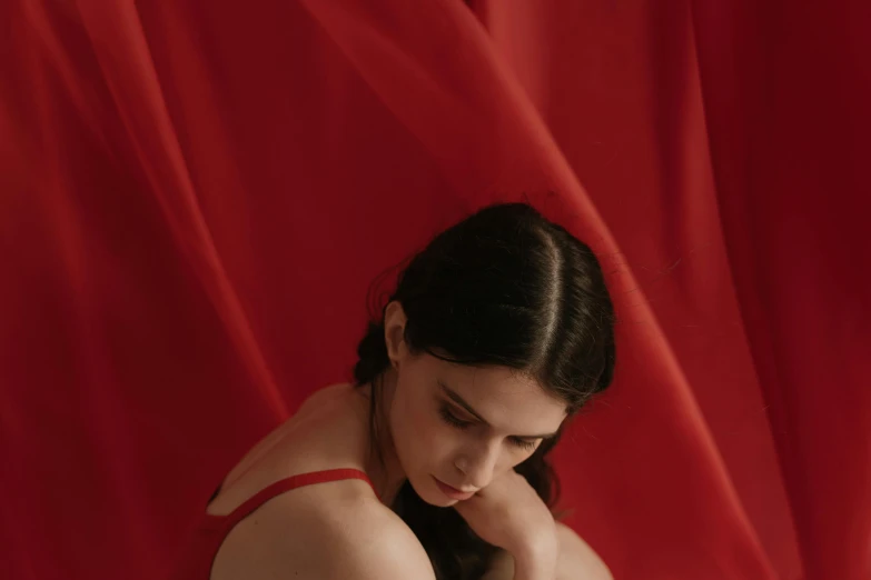 a woman is posing in front of a red curtain