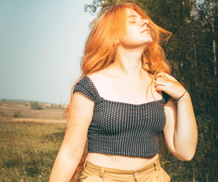 an attractive young woman standing in the grass