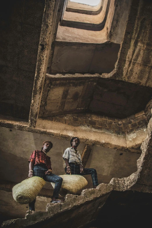 two men in a large open area sitting next to sheep