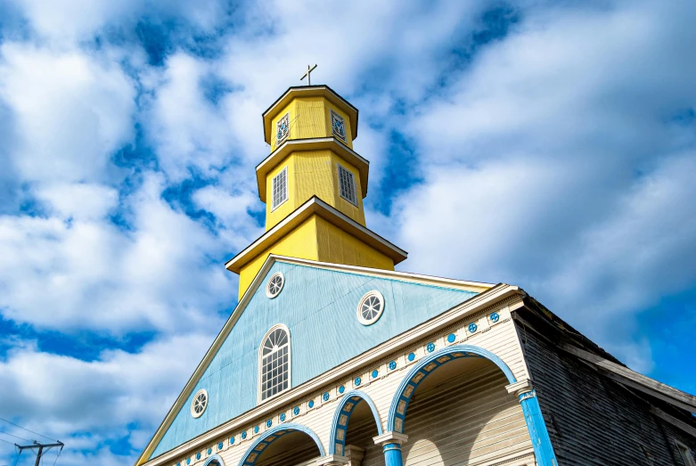 an old church with the steeple painted yellow and blue