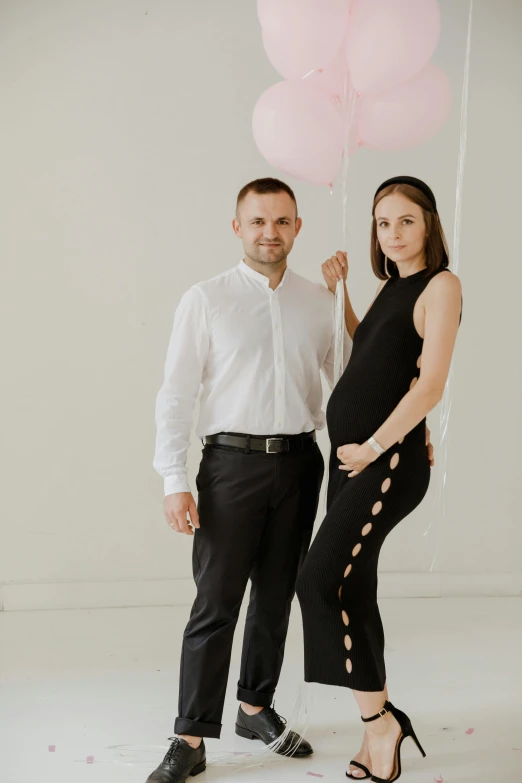 an attractive couple poses holding balloons and posing for a picture