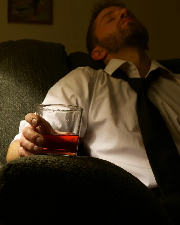 a man wearing a tie is holding a glass with drink in it