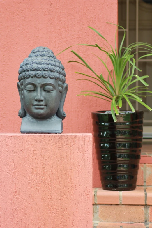 a statue sitting in front of a potted plant