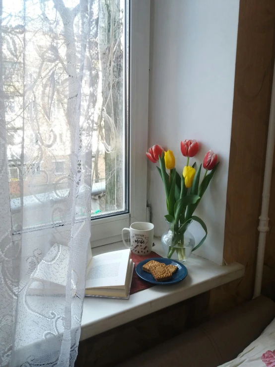 a vase filled with flowers on top of a window sill