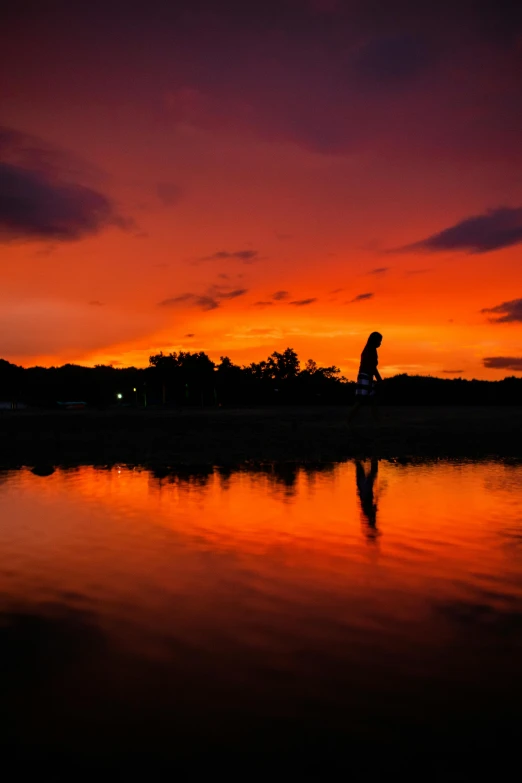 sunset with a person running along the edge of water