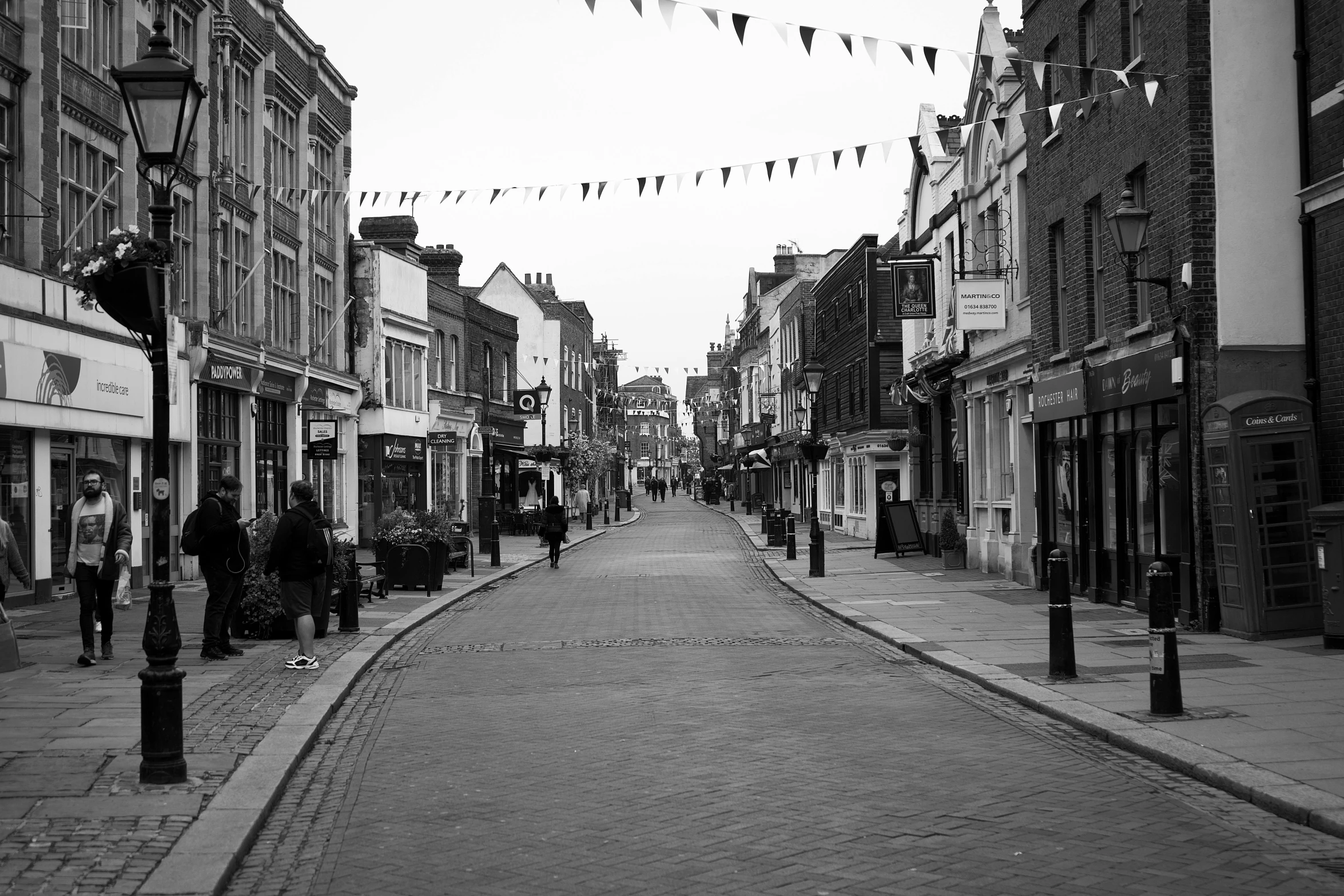 a black and white pograph of people walking on the streets