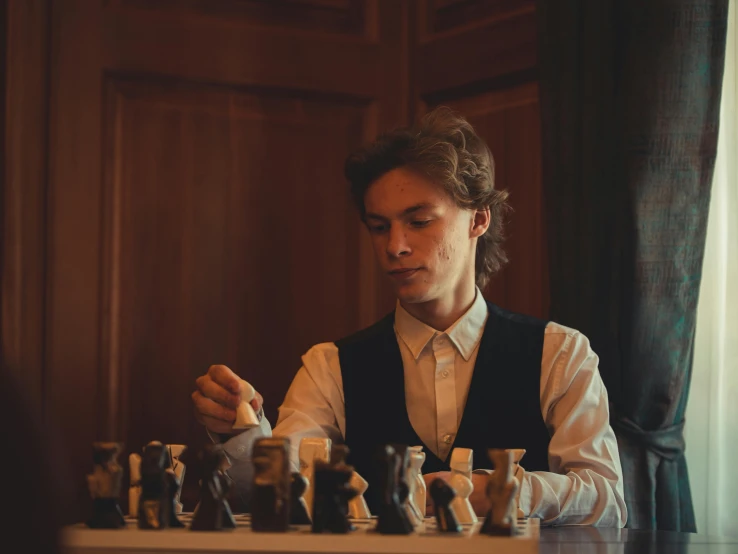 a man sitting at a table with chess pieces