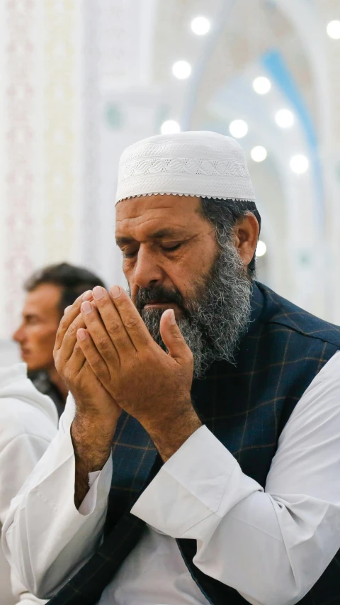 an elderly man with a beard and hands clasped together