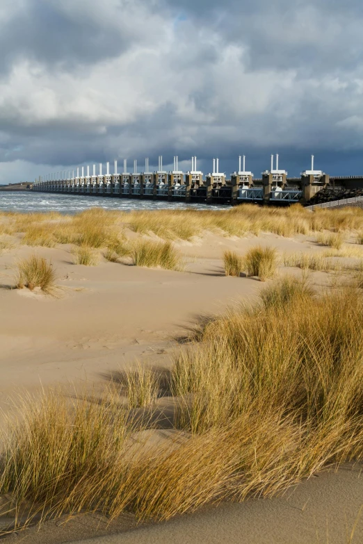 a beach with several boats on a bridge behind it