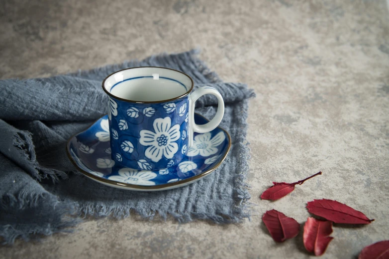 a blue and white cup and saucer with flowers