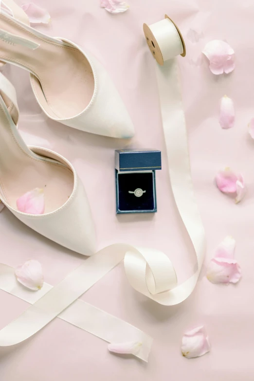 a pair of white shoes are sitting on a pink surface with ribbons and flowers