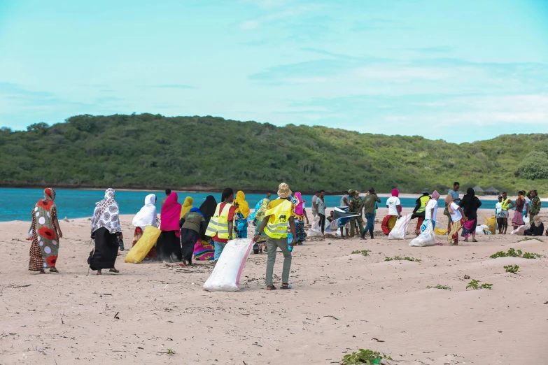 people on a beach with one woman holding her surfboard