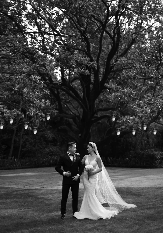 the bride and groom are holding hands while standing in a green field