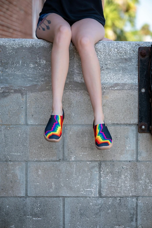 the legs of a woman sitting on a brick wall