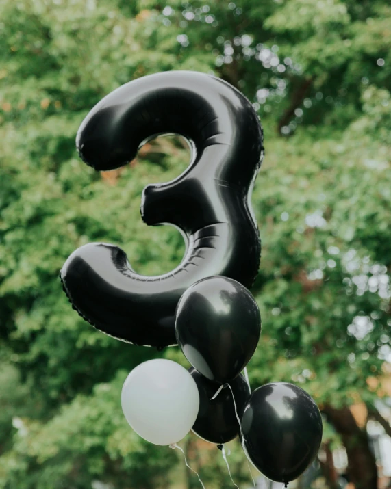 some white and black balloons on top of a number 3 balloon