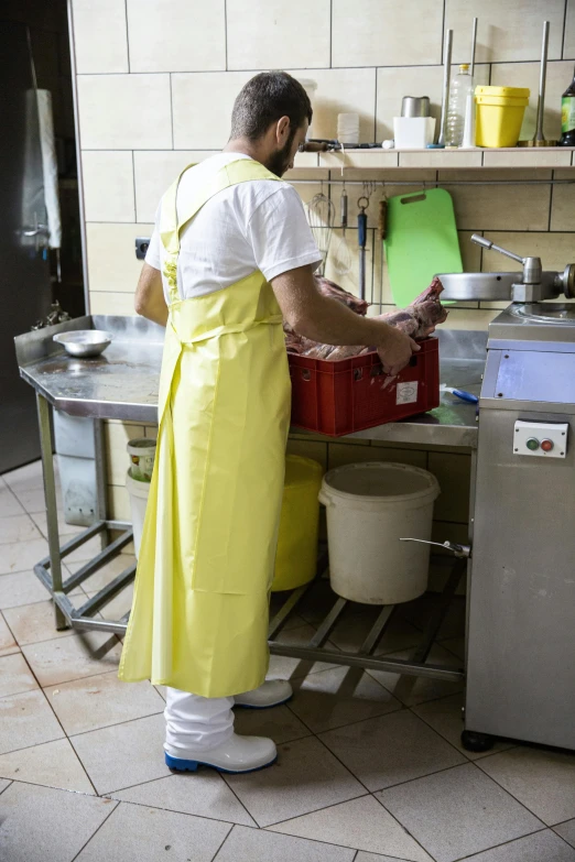 the man in the yellow apron is standing near an open sink