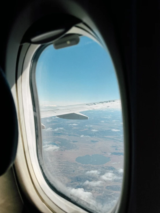 an airplane window overlooking the clouds and the ground