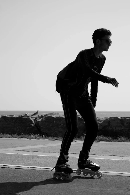 a skateboarder in dark clothes is going down a hill