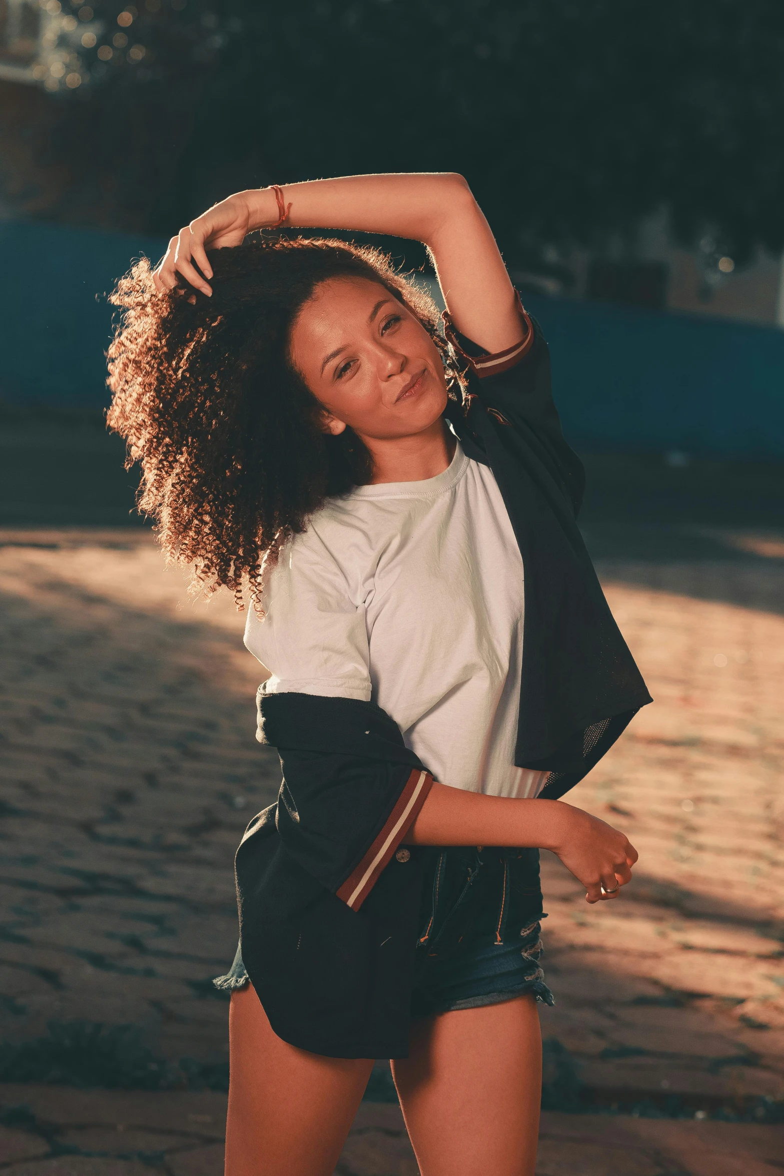 a woman with natural hair stands outdoors on the pavement