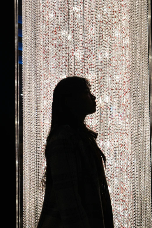 a person standing near a curtain with beading on it