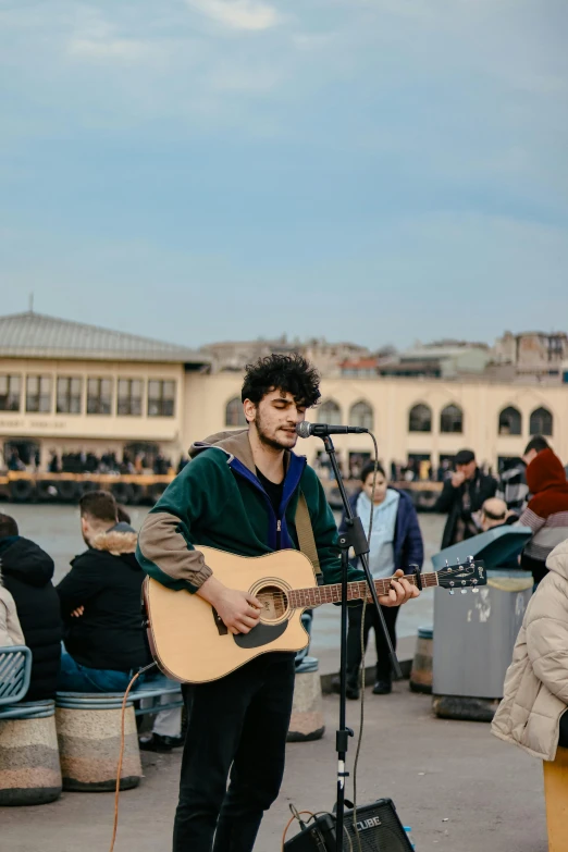 a man playing an acoustic guitar in front of a microphone