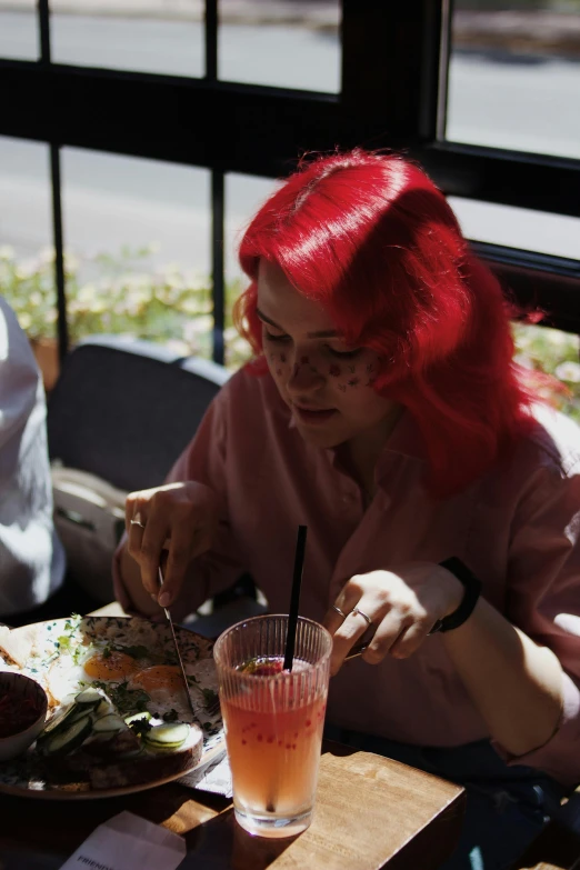 woman with red hair sitting at outdoor table enjoying pizza