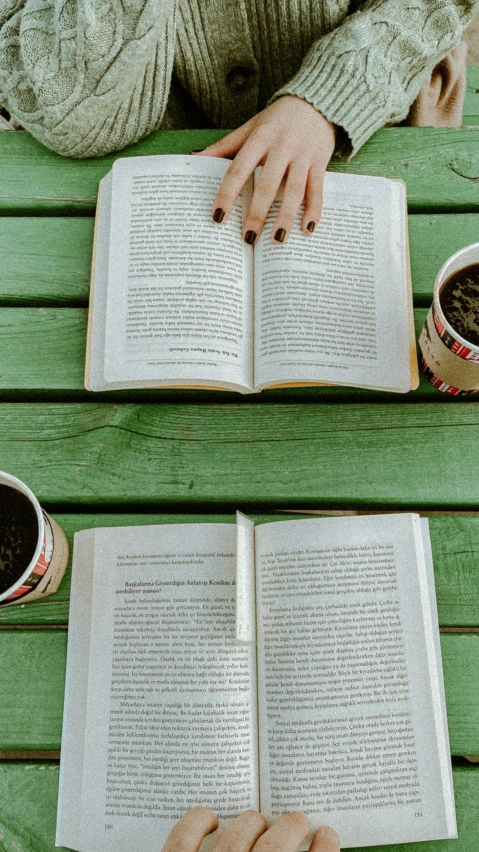 person reading a book while sitting on a bench