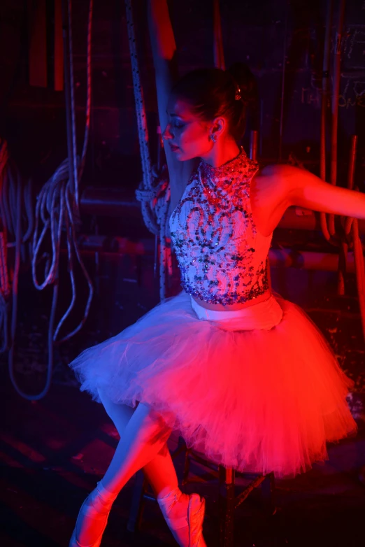 a woman is posing on a chair with a bright pink light