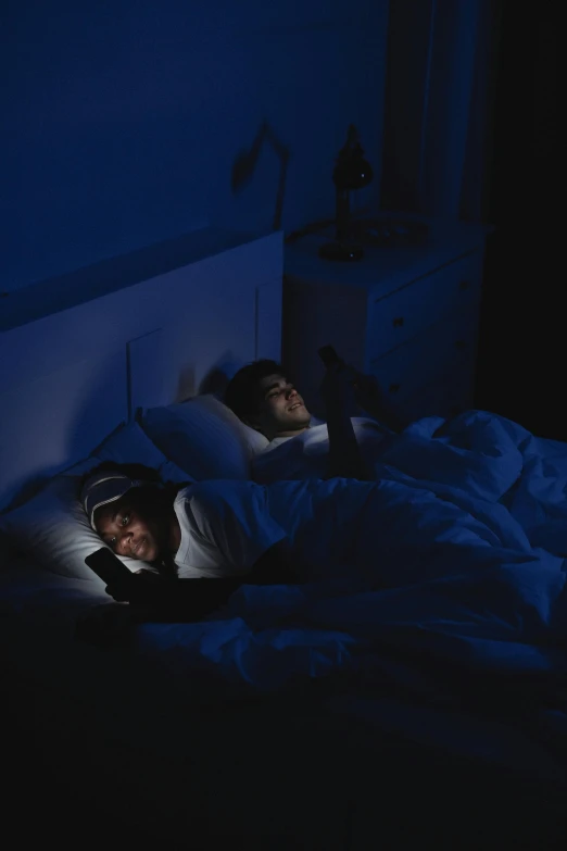 two people with headphones on laying in a bed