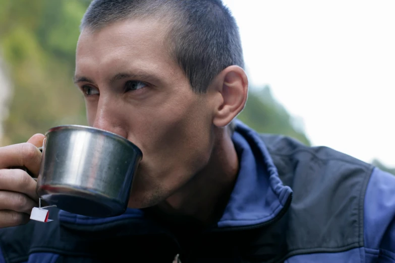 a man is drinking from a metal cup