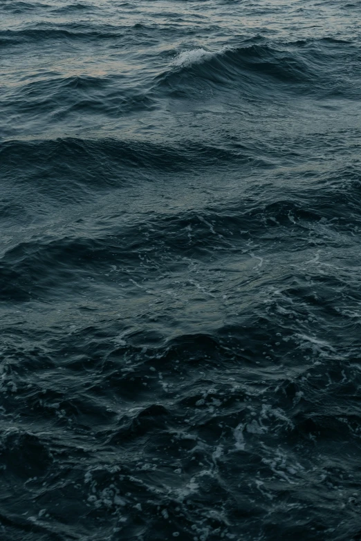 dark gray ocean with small waves and white sail