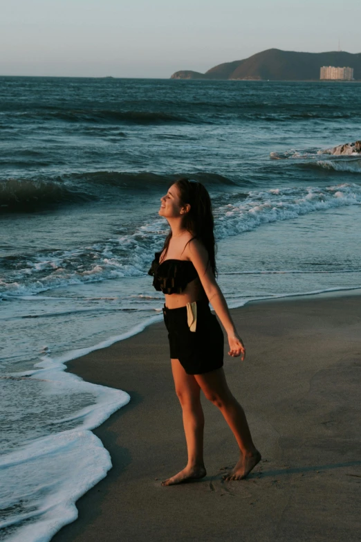 the girl is walking in the ocean along the shore