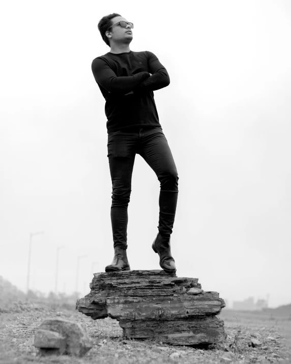 a black and white po of a man standing on a rock