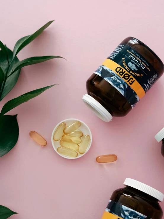 capsules of pills are scattered on pink background