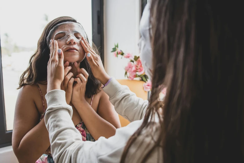 two women helping another woman adjust her eyes