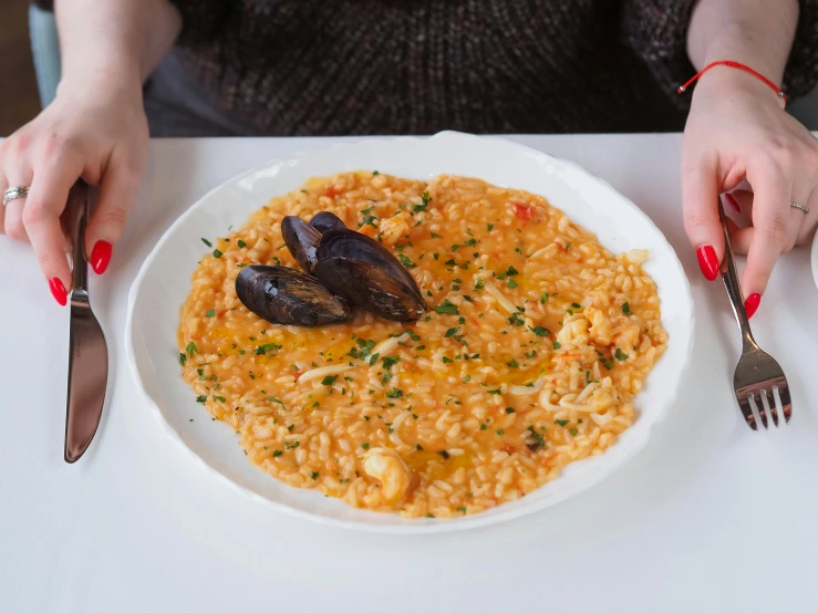 the woman is at a table with a bowl of seafood and rice