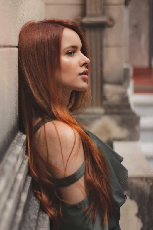 a woman with long, red hair sitting on a concrete bench