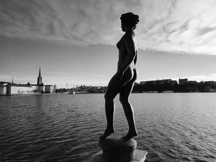 a statue of a  woman stands in the middle of a lake